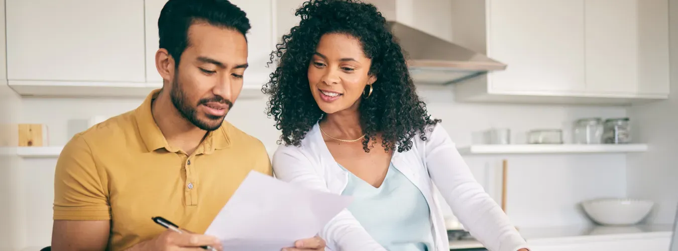 young-couple-looking-over-paperwork-in-their-kitchen